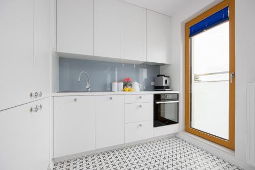 a kitchen with white cabinets and a window at Modern Apartments with Parking and AC Warsaw Suburbs by Noclegi Renters in Konstancin-Jeziorna