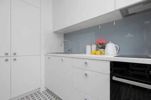 a white kitchen with a sink and a stove at Modern Apartments with Parking and AC Warsaw Suburbs by Noclegi Renters in Konstancin-Jeziorna