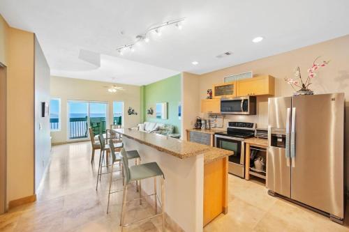 a kitchen with a refrigerator and a counter with chairs at Oceanside Escape with 3 Bedrooms Spectacular Ocean View and Pool in Galveston