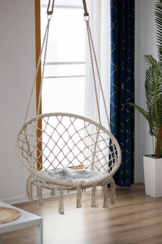 a hanging chair in a room with a plant at Modern Apartments with Parking and AC Warsaw Suburbs by Noclegi Renters in Konstancin-Jeziorna