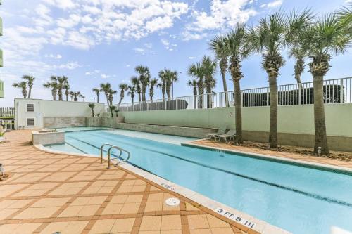 a swimming pool with palm trees next to a building at Oceanside Escape with 3 Bedrooms Spectacular Ocean View and Pool in Galveston