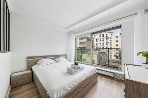 une chambre avec un lit et une grande fenêtre dans l'établissement Appartement élégant et design, à Paris