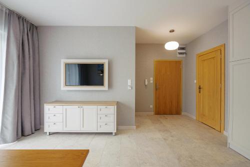 a living room with a tv and a white dresser at Apartamenty Akwamaryn in Ustka