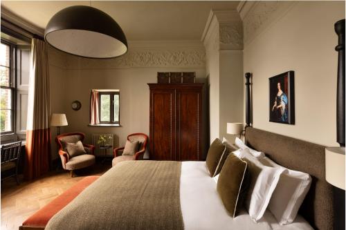 a bedroom with a large bed and chairs in a room at New Park Manor Hotel - A Luxury Family Hotel in Brockenhurst