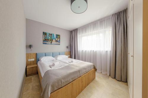 a bedroom with a bed and a large window at Apartamenty Akwamaryn in Ustka