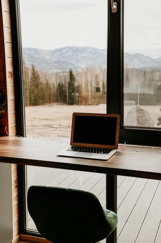 a laptop computer sitting on a desk next to a window at YATAKU DOR in Neagra Şarului
