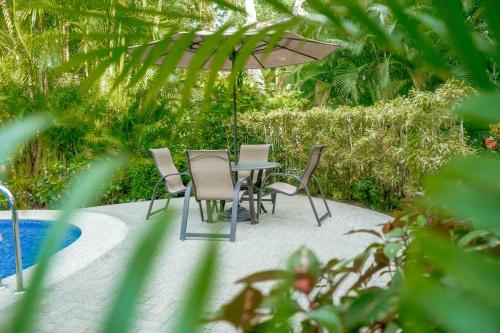 a table with chairs and an umbrella next to a pool at Secluded Garden Paradise Condo @Los Sueños in Herradura