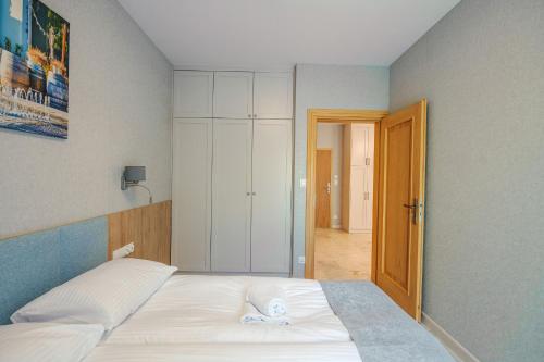 a bedroom with a bed and a door to a hallway at Apartamenty Akwamaryn in Ustka