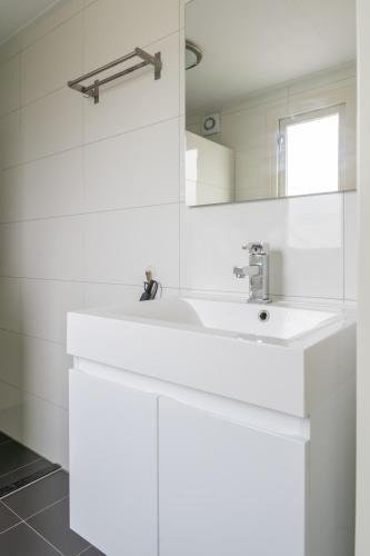 a white bathroom with a sink and a mirror at Beau Su Mer nr 1 in Kattendijke