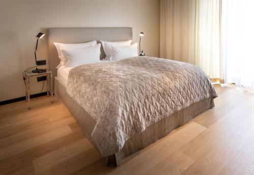 a bedroom with a large bed with white sheets and pillows at La Mansion Vi Vadi Hotel in Munich