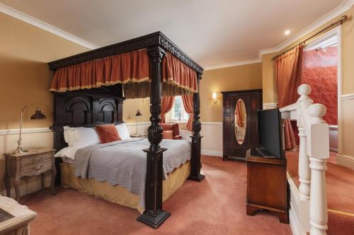 a bedroom with a canopy bed and a television at Lumley Castle Hotel in Chester-le-Street