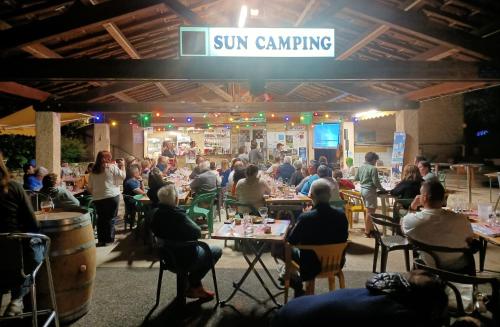 Une foule de personnes assises à table dans un restaurant dans l'établissement SUN Camping, à Sampzon
