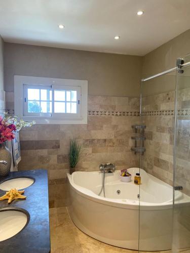 une salle de bain avec deux lavabos et une baignoire dans l'établissement La provençale, à Fontvieille