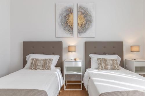 two beds in a bedroom with white sheets and pillows at Italian Experience-Villa Clair in Fermo