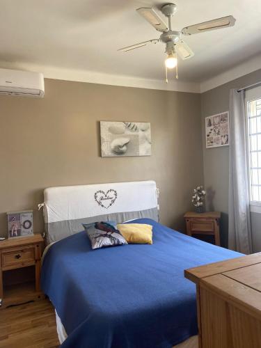 une chambre avec un lit bleu avec un ventilateur de plafond dans l'établissement La provençale, à Fontvieille