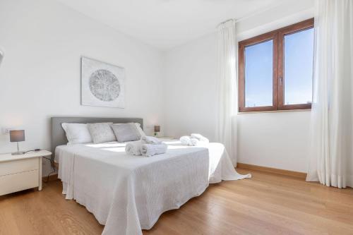 a white bedroom with a bed and a window at Italian Experience-Villa Clair in Fermo