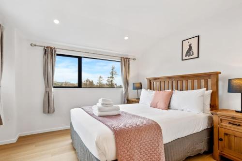 a bedroom with a large bed and a window at Ventura Delight Townhouse with Parking and Patio in Auckland
