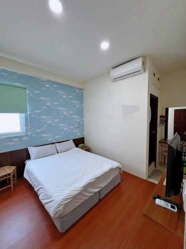 a bedroom with a large white bed and a television at Fish Luck Guesthouse in Xiaoliuqiu