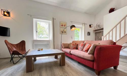 a living room with a red couch and a table at Gites-Terroirs-Occitanie in Felluns