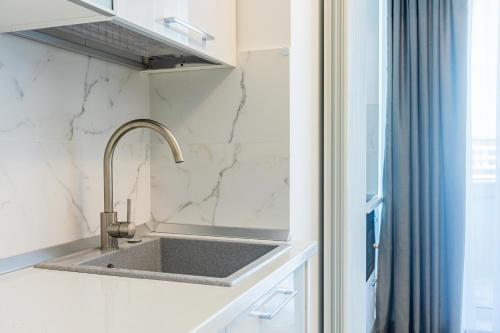 a kitchen with a sink and a blue shower curtain at Miramar - Alezzi Infinity Beach Resort in Năvodari