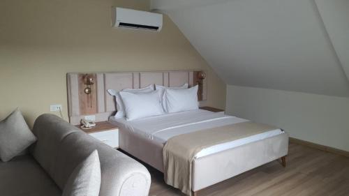 a bedroom with a bed and a couch at Petra Port Hotel in Tuzla