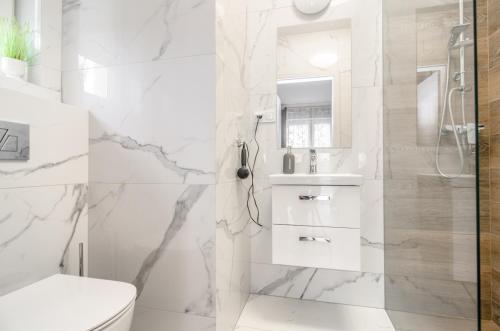 a white bathroom with a shower and a toilet at Willa Anavill in Mielno