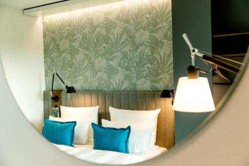 a mirror reflecting a bed with blue pillows at Motel One Bonn-Hauptbahnhof in Bonn