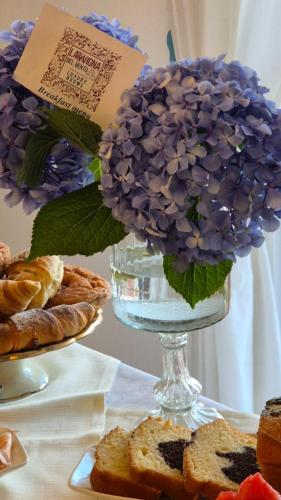 a vase with purple flowers on a table with pastries at La Vigna del Vento in Casola di Napoli