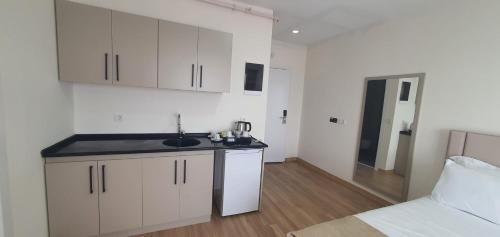 a kitchen with white cabinets and a sink and a bed at Petra Port Hotel in Tuzla