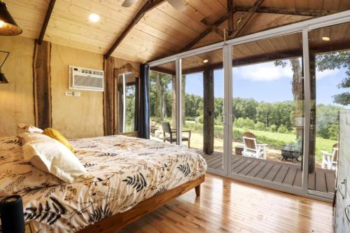 Un dormitorio con una cama y un porche con sillas. en FRISCO - Tiny Houses Of French Village, en French Village