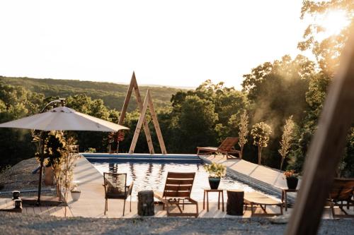 una piscina con sillas y sombrilla en TELLURIDE - Tiny Houses Of French Village, en French Village