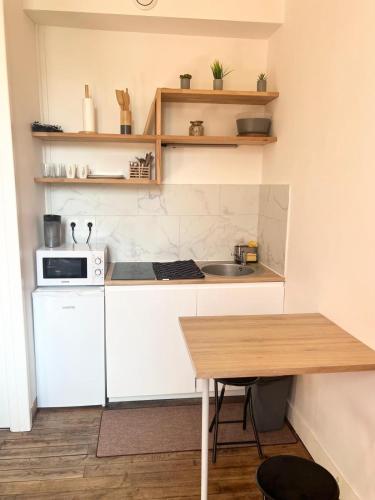 une petite cuisine avec une table et un micro-ondes dans l'établissement Charmant Studio à Poitiers, à Poitiers
