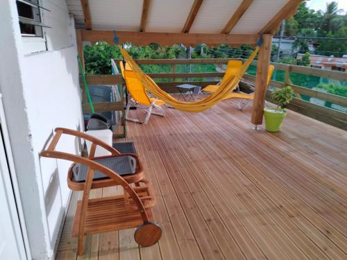a porch with a hammock and chairs on a deck at La villa du soleil 971 in Anse-Bertrand