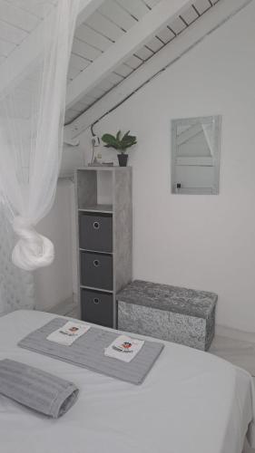 a white bedroom with a bed and a dresser at La villa du soleil 971 in Anse-Bertrand