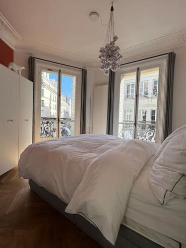 - une chambre avec un grand lit blanc et 2 fenêtres dans l'établissement Joyau au coeur du Marais - refait à neuf - luxueux, à Paris