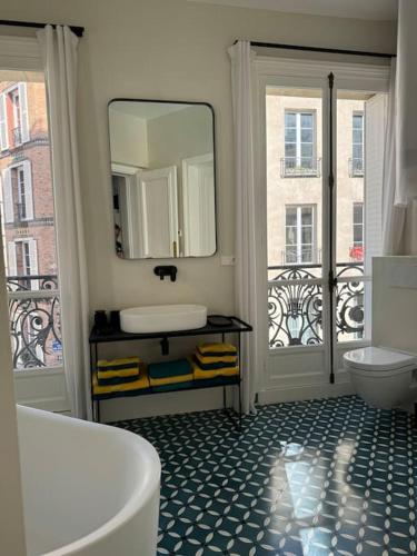 La salle de bains est pourvue d'une baignoire, d'un lavabo et de 2 fenêtres. dans l'établissement Joyau au coeur du Marais - refait à neuf - luxueux, à Paris