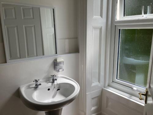 a white bathroom with a sink and a window at Serenity House Wales in Llangammarch Wells