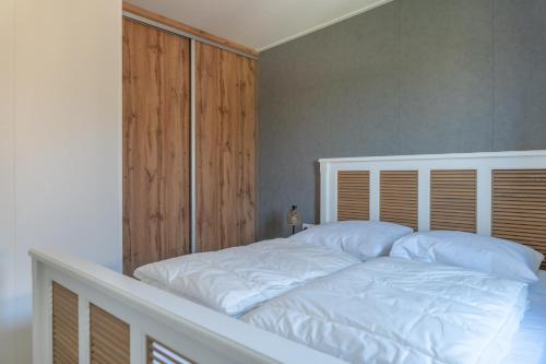 a bedroom with a white bed with a wooden headboard at Luxe 4 pers chalet op minicamping in waarde in Waarde
