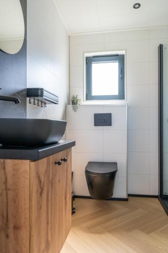 a bathroom with a black sink and a toilet at Luxe 4 pers chalet op minicamping in waarde in Waarde