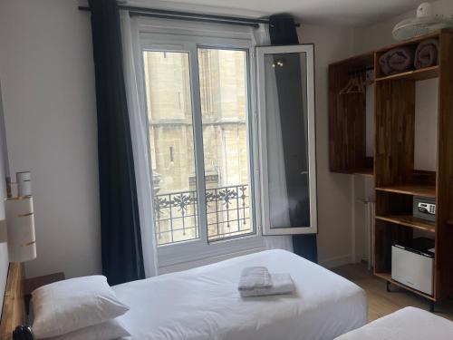 a bedroom with two beds and a large window at Hôtel De La Perdrix Rouge in Paris