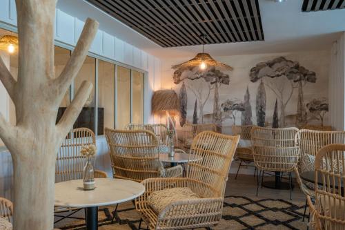 a restaurant with tables and chairs with trees on the walls at Hôtel Atalante - Relais Thalasso & Spa in Sainte-Marie-de-Ré