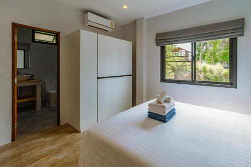 a bedroom with a white bed with a window at Naiwok Hills Resort in Haad Pleayleam