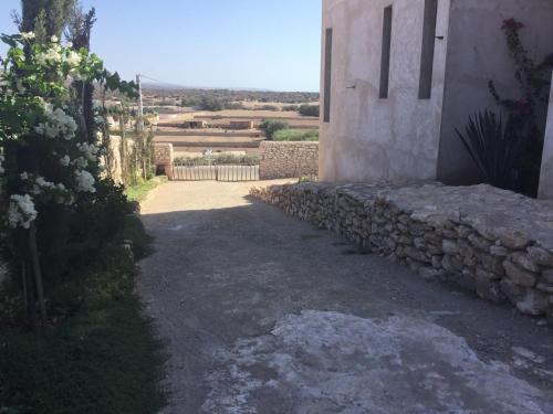 a building with a stone wall next to a driveway at Roof Top Room- Le Chemin d Iskoa in Sidi Kaouki