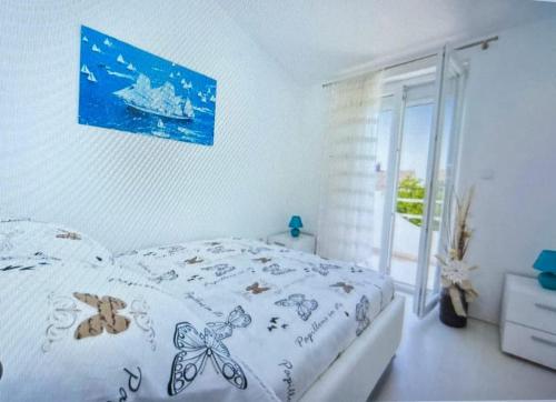 a white bedroom with a bed with a blue picture on the wall at Villa Sonja in Biograd na Moru