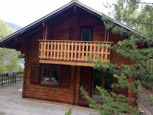 eine Blockhütte mit Balkon auf einer Terrasse in der Unterkunft L'ARGOUSIER Chalet 6 à 8 personnes Enchastrayes Barcelonnette in Enchastrayes