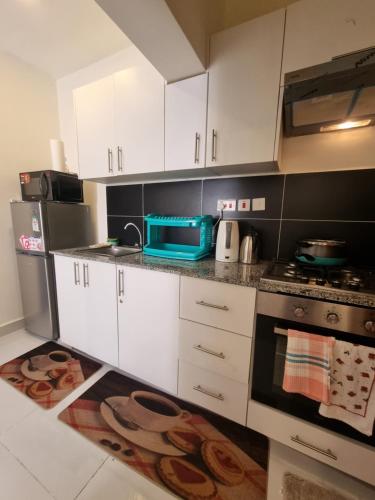 SyokimauにあるLuxore Rozina Airport View Apartment, Syokimau Nairobiの白いキャビネットとコンロ付きオーブンを備えたキッチン