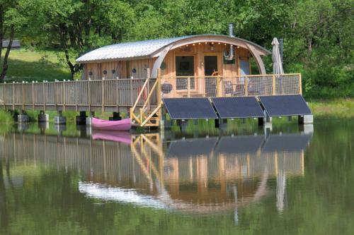 a house on a dock on a body of water at Domaine de la Clauzade in Saint-Germain-les-Vergnes