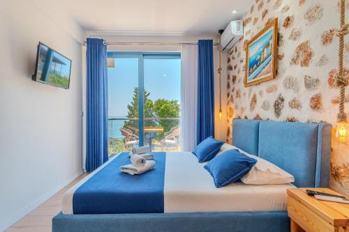 Un dormitorio con una cama azul y una gran ventana. en Alex Boutique Hotel, en Himare