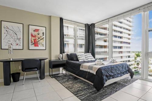 ein Schlafzimmer mit einem Bett, einem Schreibtisch und Fenstern in der Unterkunft Relaxing Escape Oceanfront Pool Gem On The Beach in Fort Lauderdale