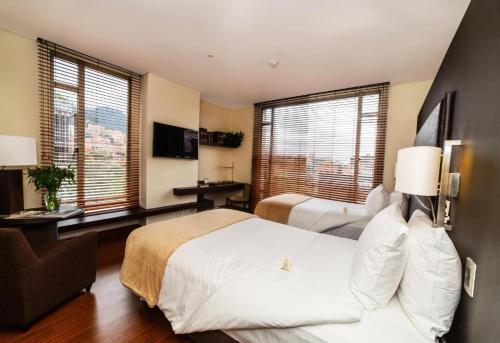 a hotel room with two beds and two windows at Hotel Cabrera Imperial By key 33 in Bogotá